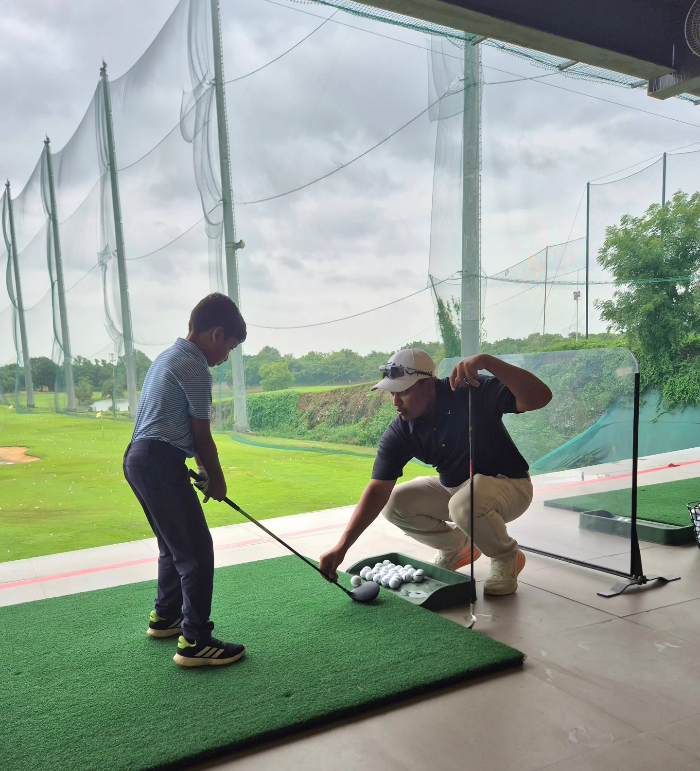 Coach Amit Khaitan guiding a junior golfer at the driving range