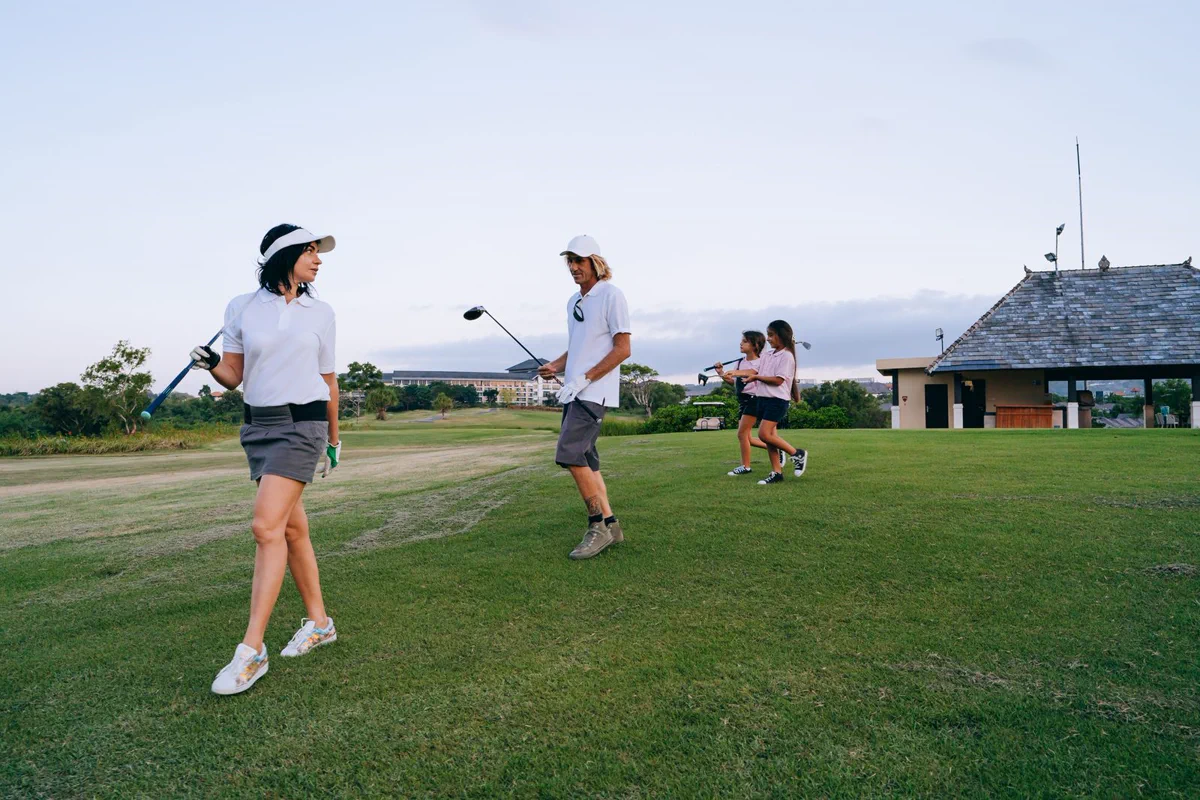 Parents and children walking together with golf clubs on the course